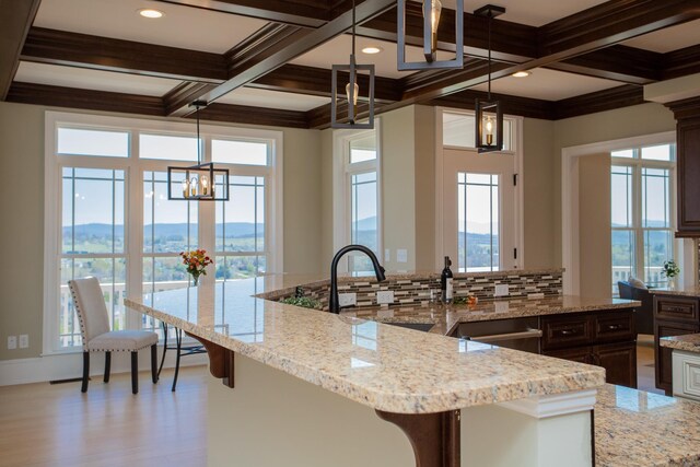 kitchen with coffered ceiling, decorative light fixtures, a mountain view, and light stone counters