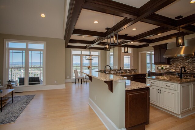 kitchen featuring decorative light fixtures, white cabinetry, a breakfast bar area, light stone counters, and a spacious island