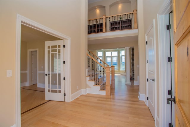 foyer entrance with a towering ceiling, light hardwood / wood-style flooring, and french doors