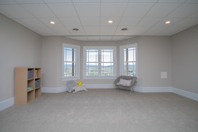 carpeted empty room featuring a drop ceiling