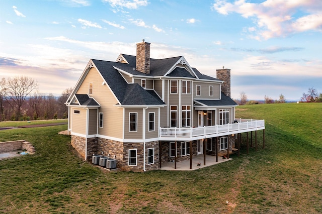 back house at dusk with a wooden deck, a yard, central air condition unit, and a patio area