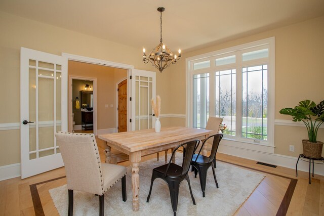 dining room featuring a notable chandelier, light hardwood / wood-style flooring, and french doors