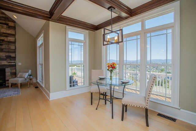 dining area with an inviting chandelier, coffered ceiling, light hardwood / wood-style floors, a mountain view, and beam ceiling