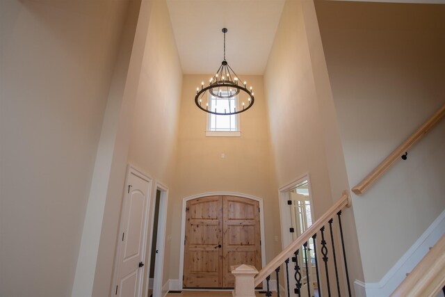 entryway featuring a towering ceiling and a chandelier