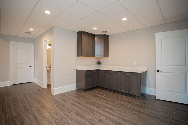 bar with a drop ceiling and dark wood-type flooring