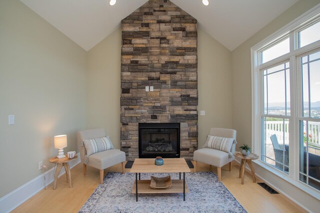 interior space with vaulted ceiling, a stone fireplace, and light hardwood / wood-style floors