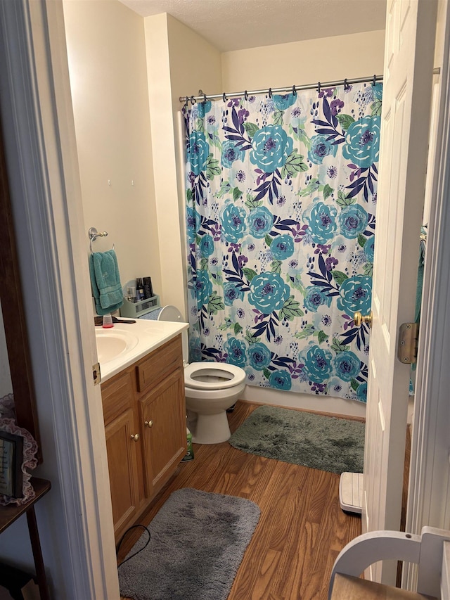 bathroom featuring vanity, wood finished floors, toilet, and shower / bathtub combination with curtain