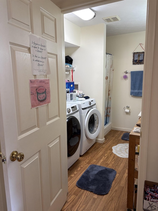 washroom with visible vents, wood finished floors, laundry area, independent washer and dryer, and baseboards