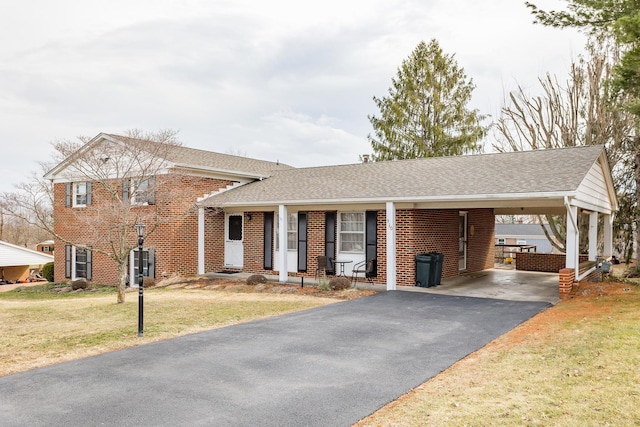 split level home with aphalt driveway, roof with shingles, a front lawn, a carport, and brick siding