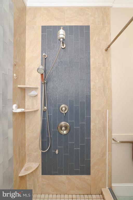 bathroom featuring crown molding and a tile shower