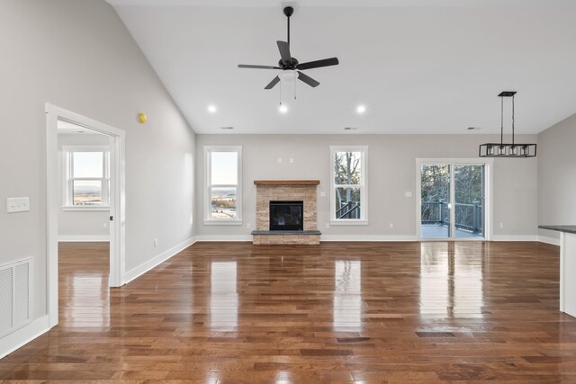 unfurnished living room with dark wood-type flooring, ceiling fan, and a stone fireplace