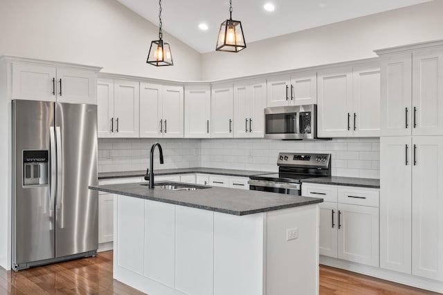 kitchen featuring decorative light fixtures, white cabinetry, sink, a kitchen island with sink, and stainless steel appliances