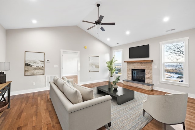 living room featuring ceiling fan, wood-type flooring, a stone fireplace, and high vaulted ceiling