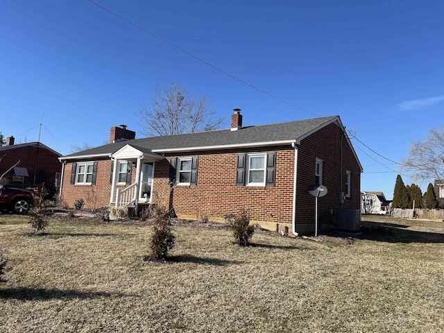 view of front of home with brick siding, a chimney, a shingled roof, central AC unit, and a front yard