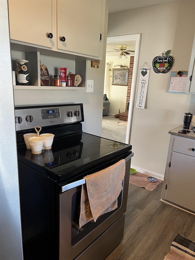 kitchen with dark wood-style flooring, light countertops, electric range, white cabinets, and baseboards