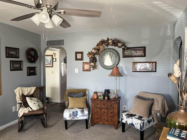 living area featuring arched walkways, carpet, a ceiling fan, and baseboards