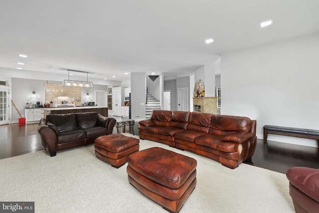 living area featuring stairs, a fireplace, and recessed lighting