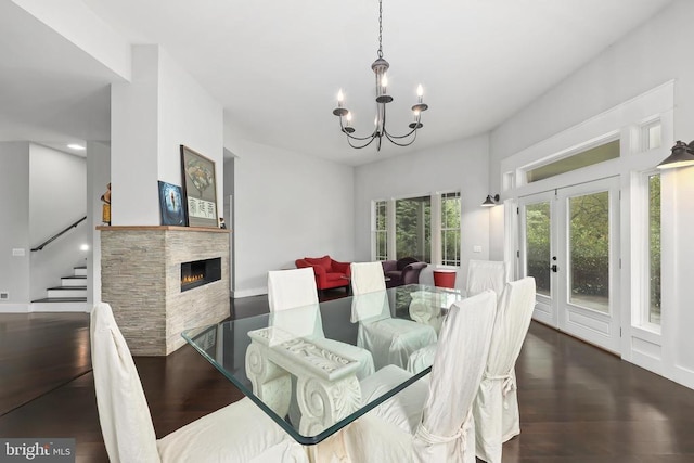 dining room with a chandelier, a tile fireplace, french doors, and wood finished floors