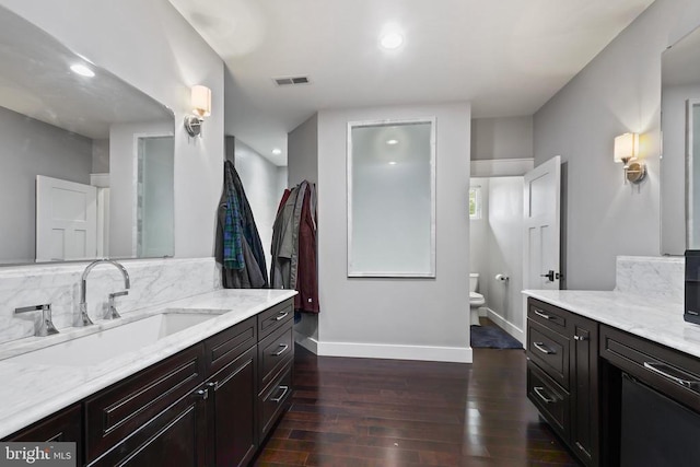 bathroom featuring baseboards, visible vents, decorative backsplash, toilet, and wood finished floors