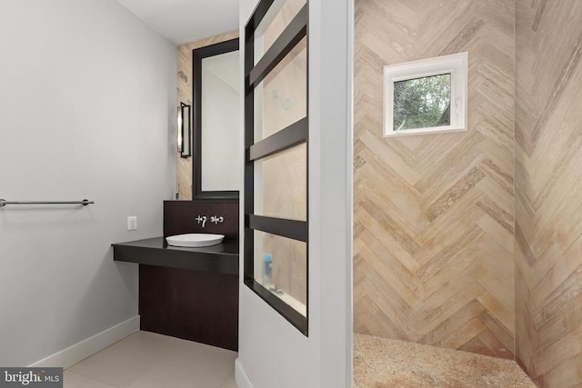 bathroom with baseboards, a tile shower, and vanity