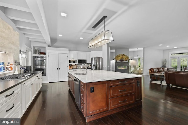 kitchen featuring stainless steel appliances, a sink, white cabinets, backsplash, and dark wood finished floors