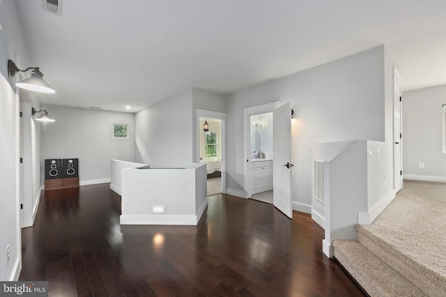 hallway with visible vents, baseboards, and wood finished floors