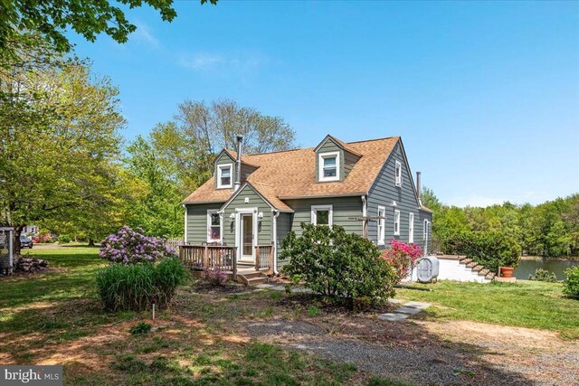 cape cod-style house featuring a shingled roof and a front lawn
