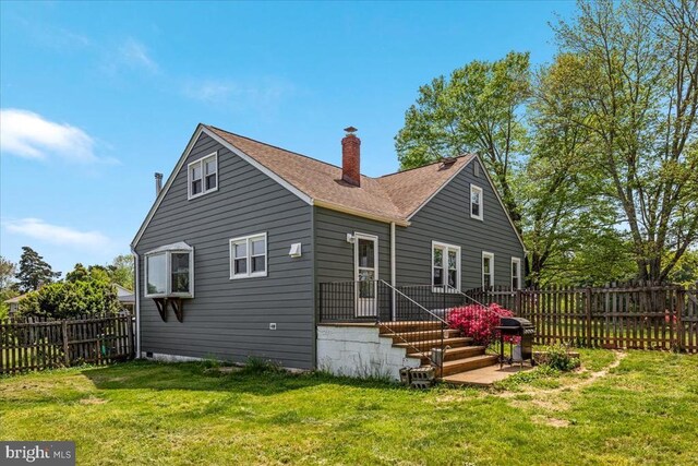 back of property featuring a fenced backyard, a chimney, and a yard