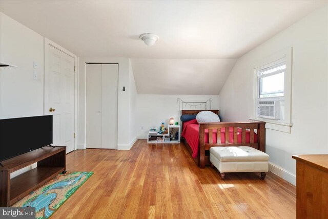 bedroom with baseboards, wood finished floors, lofted ceiling, and cooling unit
