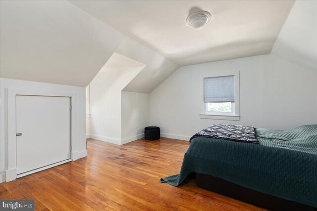 bedroom featuring baseboards, wood finished floors, and lofted ceiling