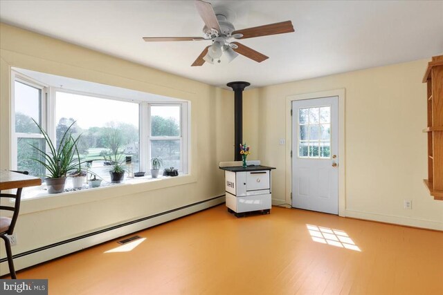 interior space with a baseboard radiator, a wood stove, a ceiling fan, baseboards, and light wood-type flooring