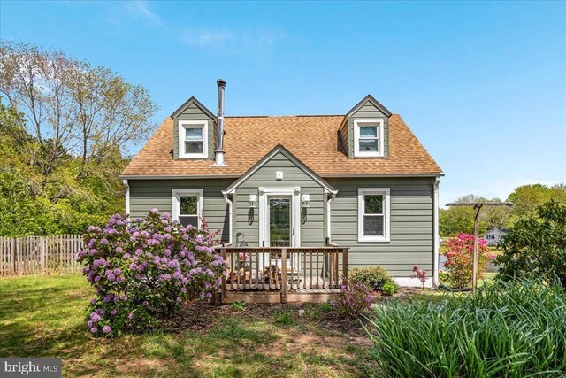 back of house featuring roof with shingles, fence, and a yard