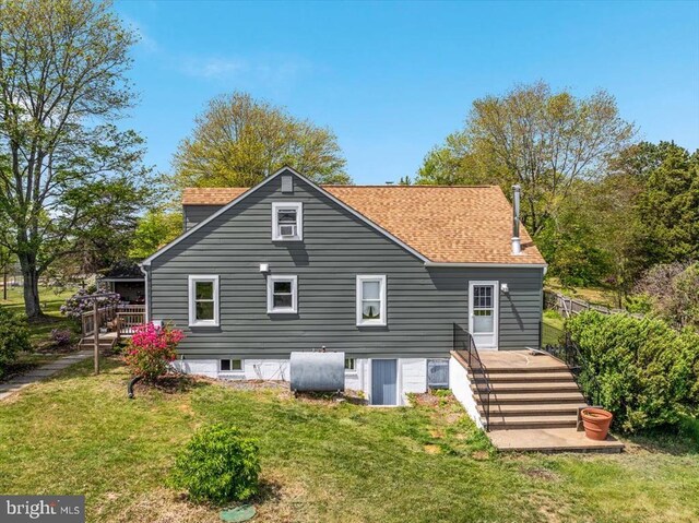 back of property featuring a yard, heating fuel, and roof with shingles