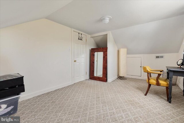 interior space featuring baseboards, vaulted ceiling, light colored carpet, and visible vents