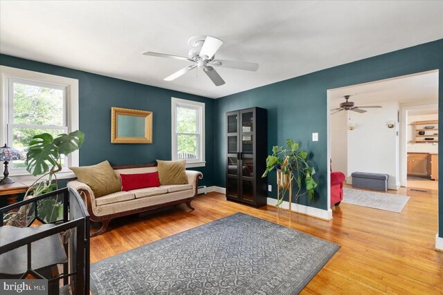 living area featuring light wood-style floors, ceiling fan, and a wealth of natural light