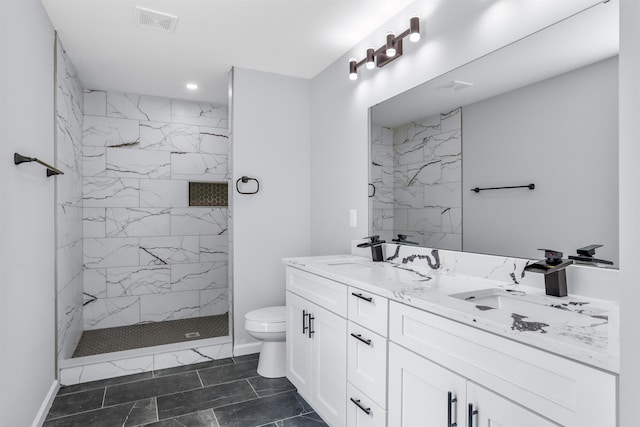 bathroom featuring vanity, toilet, and a tile shower