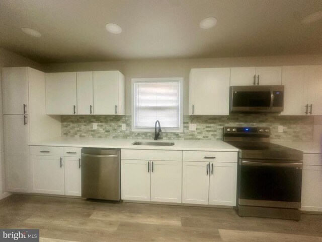 kitchen featuring appliances with stainless steel finishes, sink, white cabinets, and decorative backsplash