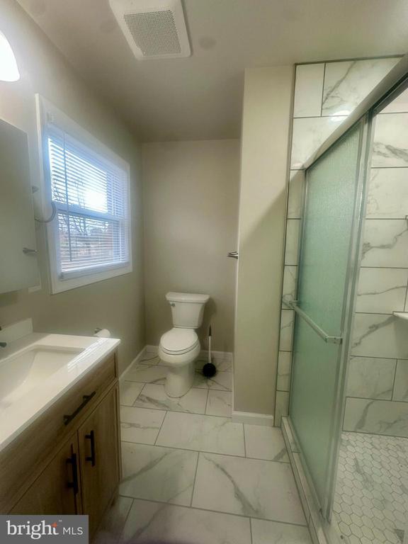 bathroom featuring vanity, toilet, and a shower with shower door