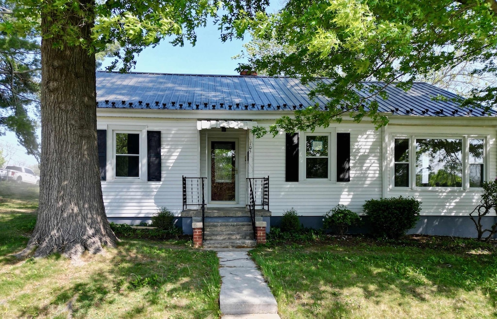 bungalow featuring metal roof and a front yard