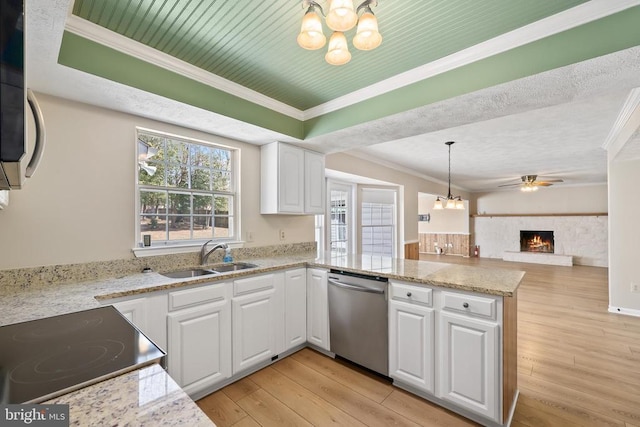 kitchen featuring a peninsula, ornamental molding, a sink, light wood-style floors, and appliances with stainless steel finishes