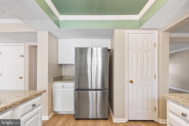 kitchen with crown molding, white cabinets, light wood finished floors, and freestanding refrigerator