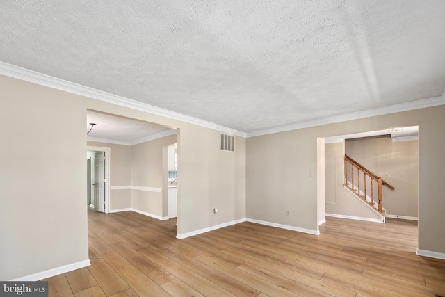 unfurnished room with light wood-type flooring, visible vents, baseboards, and stairs