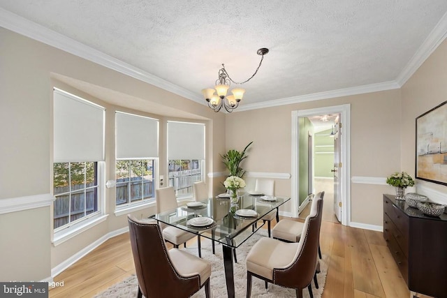 dining area featuring light wood finished floors, a notable chandelier, a textured ceiling, and baseboards