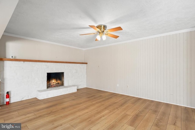 unfurnished living room with crown molding, ceiling fan, a fireplace, hardwood / wood-style flooring, and a textured ceiling