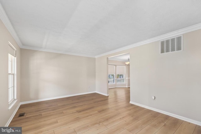 unfurnished room with ornamental molding, baseboards, visible vents, and light wood-type flooring