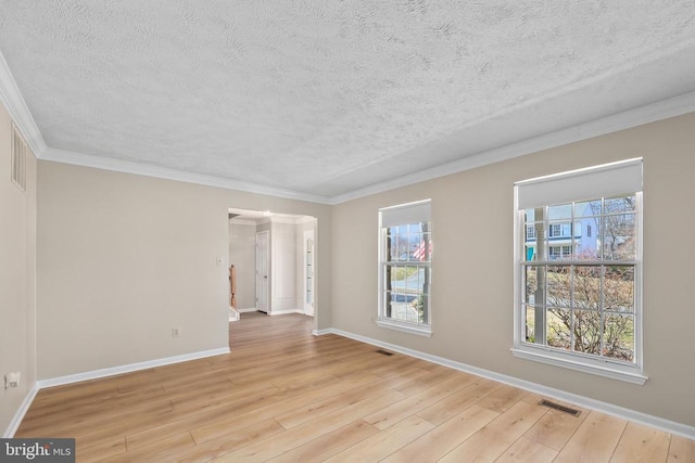 spare room featuring wood finished floors, visible vents, baseboards, a textured ceiling, and crown molding