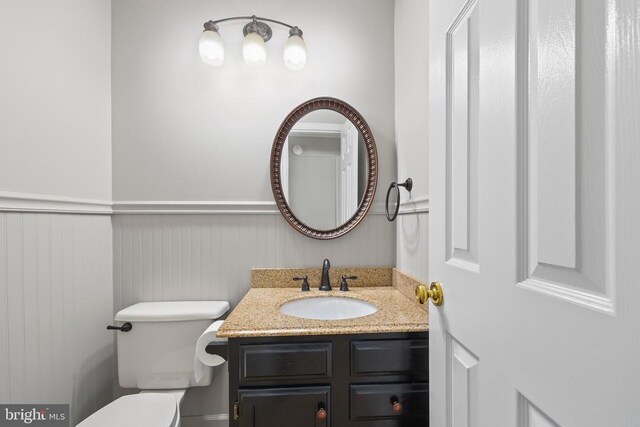 bathroom featuring toilet, wainscoting, and vanity