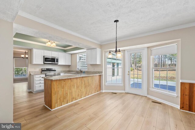 kitchen with white cabinets, appliances with stainless steel finishes, light wood-style floors, and ornamental molding