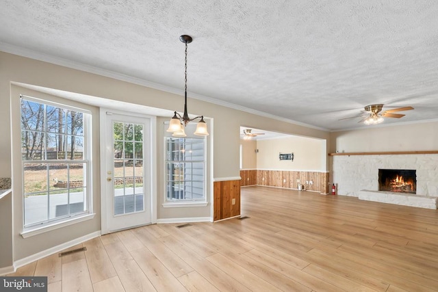 unfurnished living room featuring a wainscoted wall, wood finished floors, visible vents, and ceiling fan