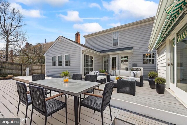 wooden deck with outdoor dining space, an outdoor hangout area, and fence